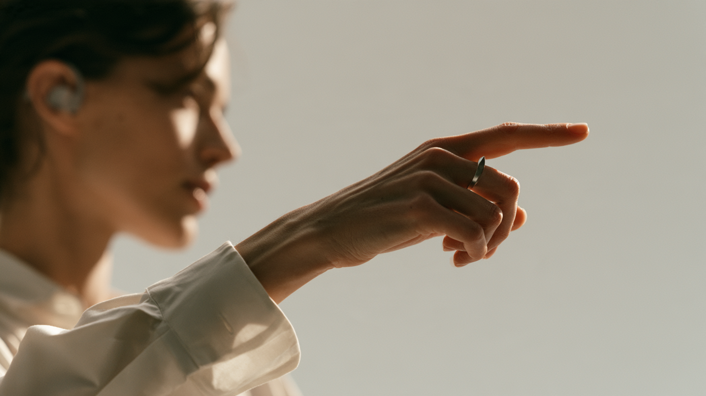 A person wearing an earpiece and ring points into the physical world.